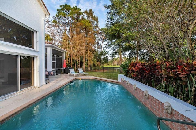 view of pool with pool water feature, a sunroom, and a patio