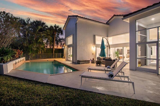 pool at dusk featuring an outdoor living space and a patio area