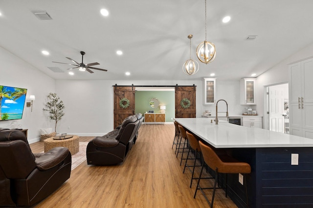 kitchen with white cabinets, sink, light hardwood / wood-style floors, and a barn door