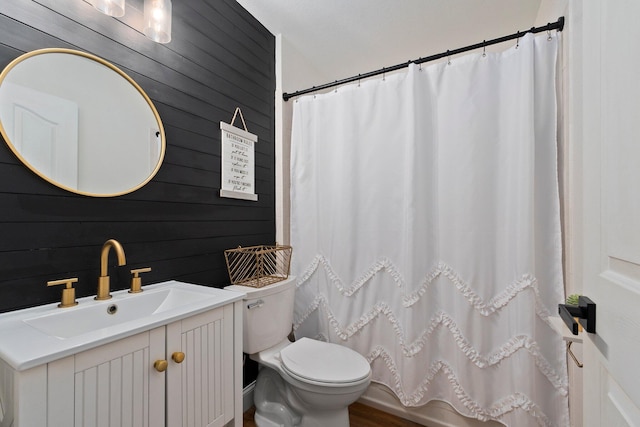 bathroom featuring wood walls, wood-type flooring, toilet, and vanity