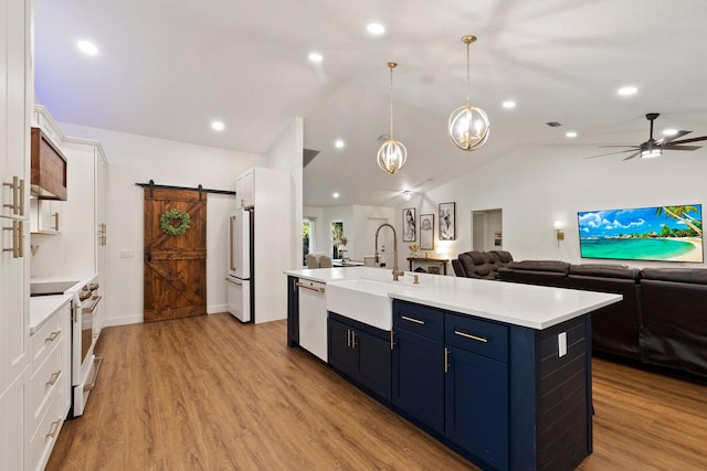 kitchen with a barn door, white appliances, ceiling fan with notable chandelier, white cabinetry, and light hardwood / wood-style flooring