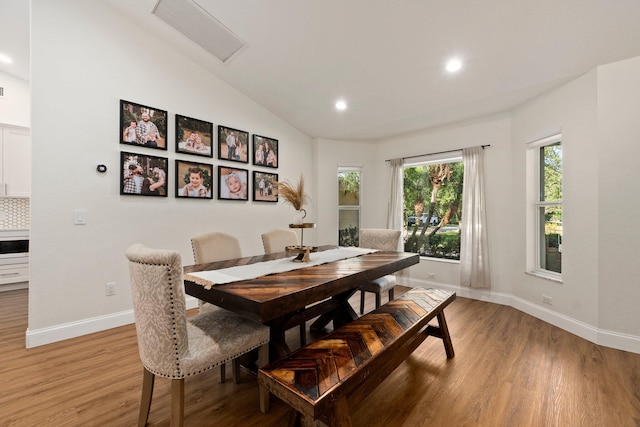 dining area featuring wood-type flooring and vaulted ceiling