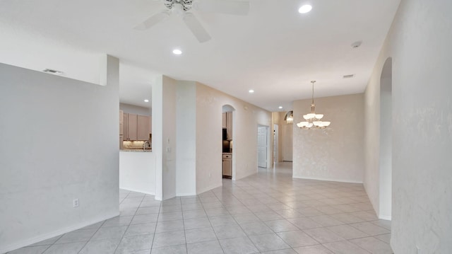 tiled spare room with ceiling fan with notable chandelier