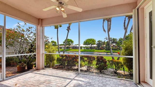 unfurnished sunroom with a water view and ceiling fan