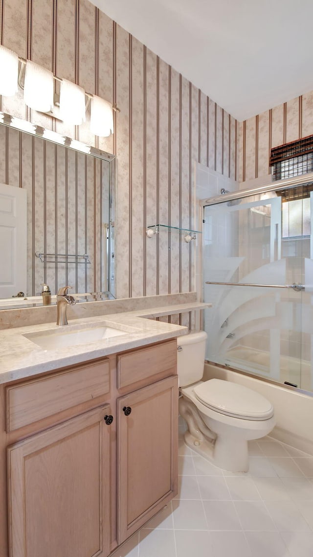 full bathroom featuring tile floors, bath / shower combo with glass door, toilet, and vanity