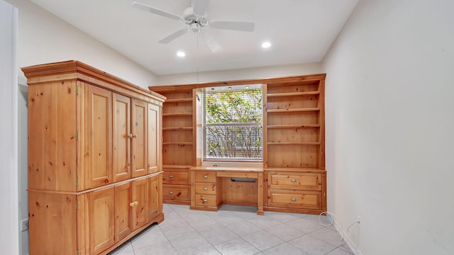 interior space with built in desk, ceiling fan, and light tile floors