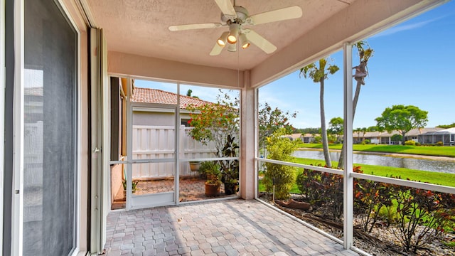 unfurnished sunroom featuring ceiling fan and a water view