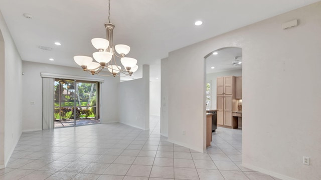 tiled spare room featuring a notable chandelier