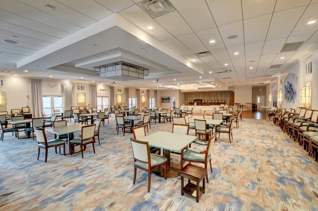 carpeted dining space with a raised ceiling