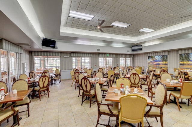 tiled dining room featuring ceiling fan and a raised ceiling