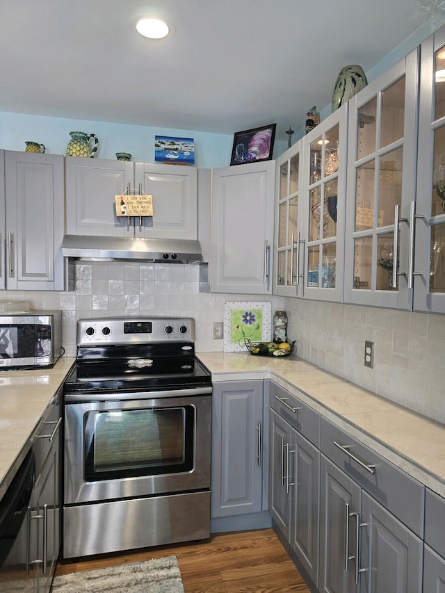 kitchen with appliances with stainless steel finishes, light wood-type flooring, gray cabinets, and tasteful backsplash