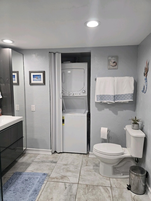 bathroom with vanity, stacked washer and dryer, and toilet