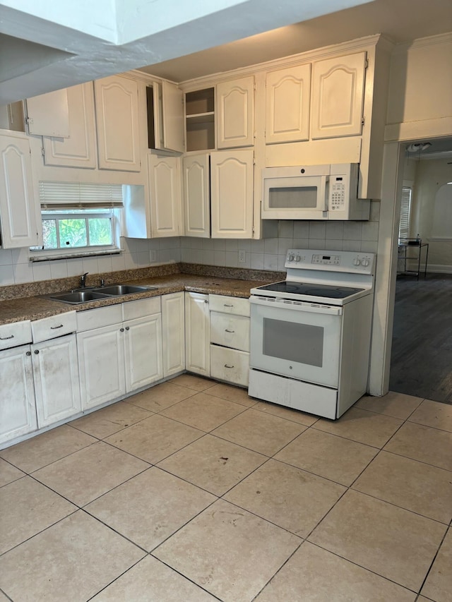 kitchen with sink, light wood-type flooring, decorative backsplash, and white appliances