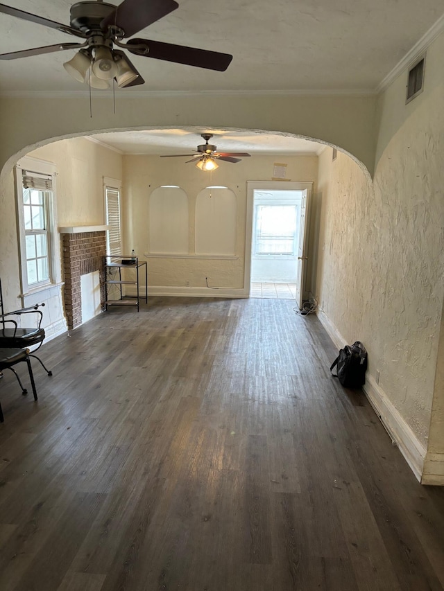 unfurnished living room featuring ceiling fan, dark wood-type flooring, and a brick fireplace