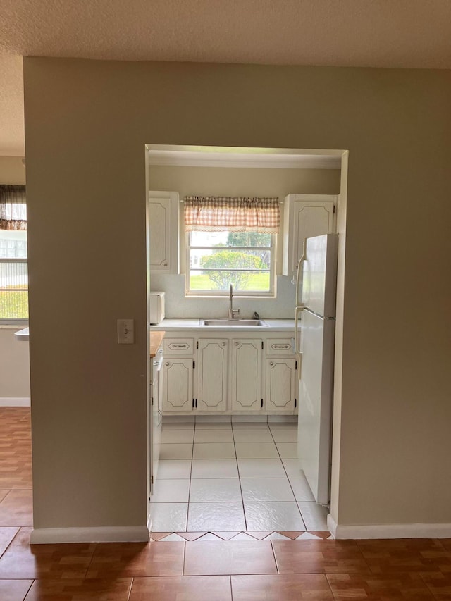 kitchen featuring sink, white cabinetry, white appliances, and light tile patterned floors