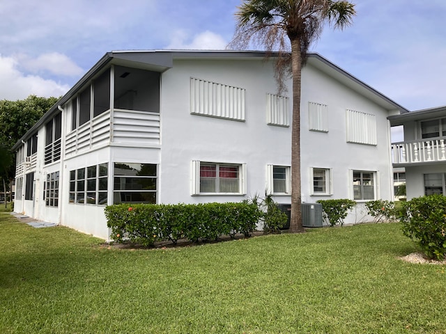 view of side of property with cooling unit, a lawn, and a balcony