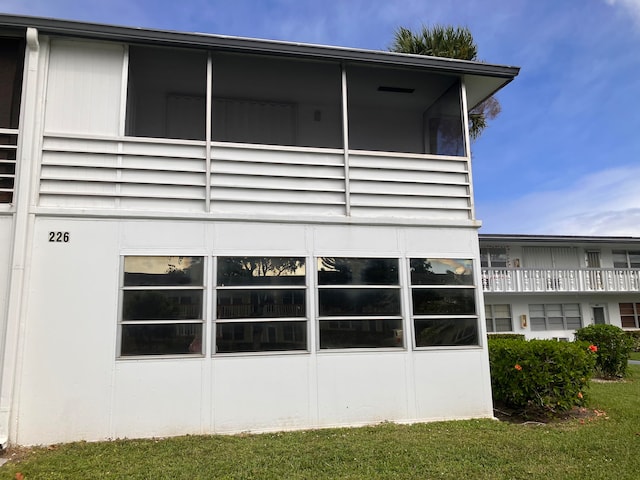 view of home's exterior featuring a balcony and a lawn