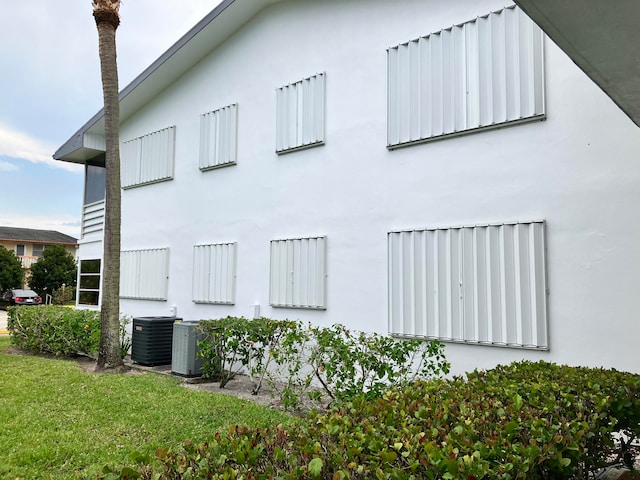 view of side of property featuring cooling unit and a lawn