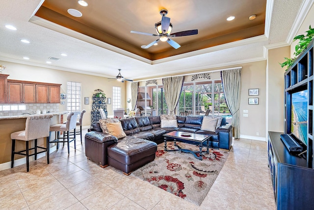 tiled living room with a healthy amount of sunlight, ceiling fan, and a tray ceiling