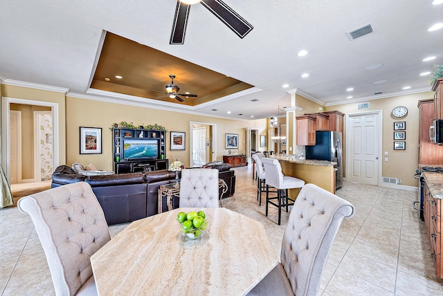 dining area with a tray ceiling, crown molding, ceiling fan, and light tile flooring