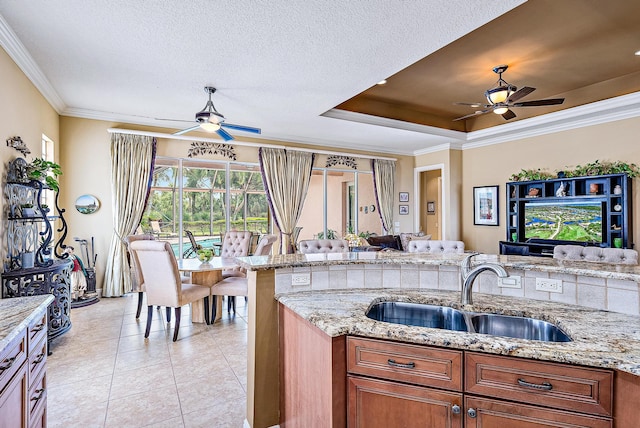 kitchen featuring ceiling fan, a tray ceiling, and light stone counters