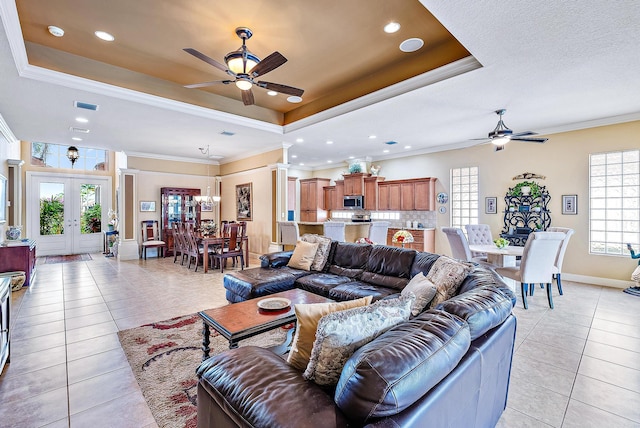 tiled living room featuring french doors, ceiling fan, and a raised ceiling