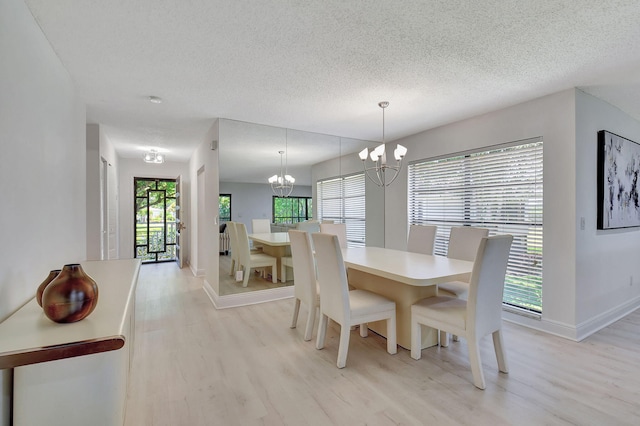 dining space featuring light hardwood / wood-style floors, a chandelier, and a textured ceiling