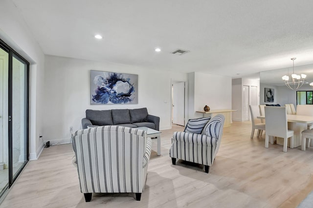 living room with light hardwood / wood-style flooring, a notable chandelier, and a textured ceiling