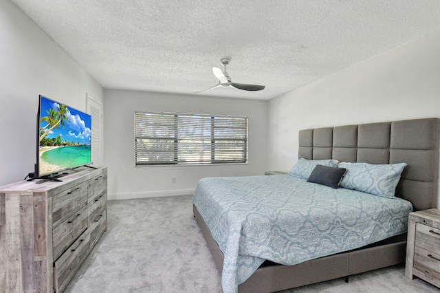 bedroom featuring light colored carpet, ceiling fan, and a textured ceiling