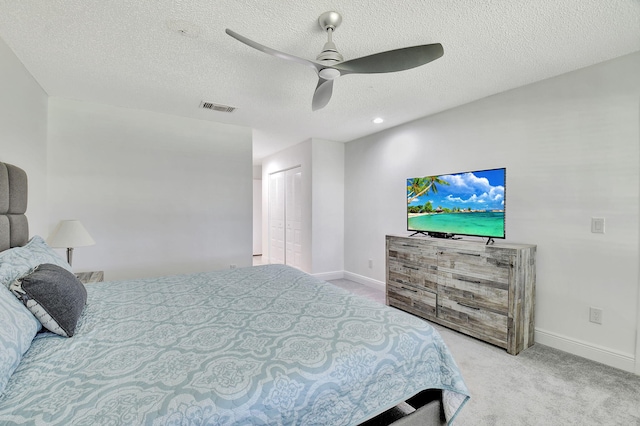 carpeted bedroom featuring a closet, ceiling fan, and a textured ceiling