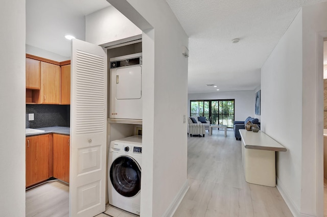 laundry room featuring stacked washer / dryer and light wood-type flooring