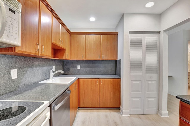 kitchen with backsplash, light hardwood / wood-style floors, stainless steel dishwasher, and sink