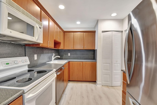 kitchen with sink, light hardwood / wood-style floors, backsplash, and stainless steel appliances