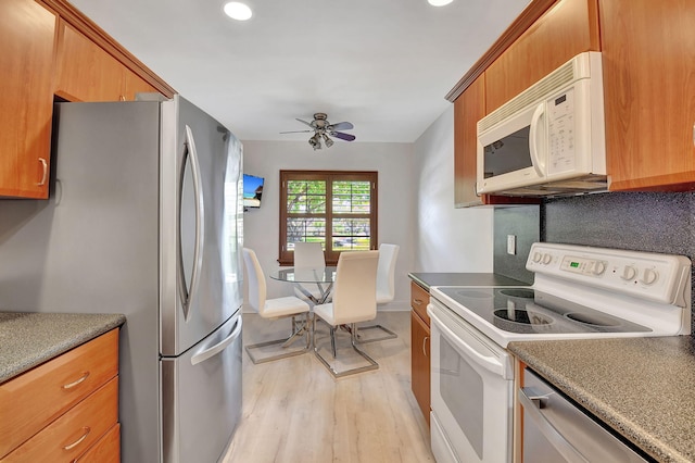 kitchen with ceiling fan, backsplash, light wood-type flooring, and stainless steel appliances