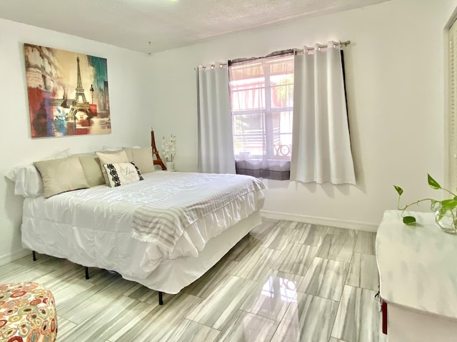 bedroom with a textured ceiling and baseboards