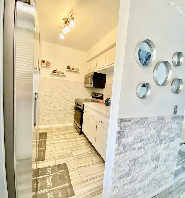 kitchen featuring stainless steel appliances, wood finish floors, light countertops, and white cabinetry