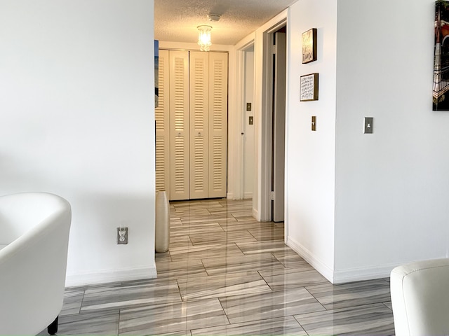 corridor featuring a textured ceiling and baseboards