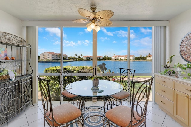 sunroom with ceiling fan, a water view, and a healthy amount of sunlight