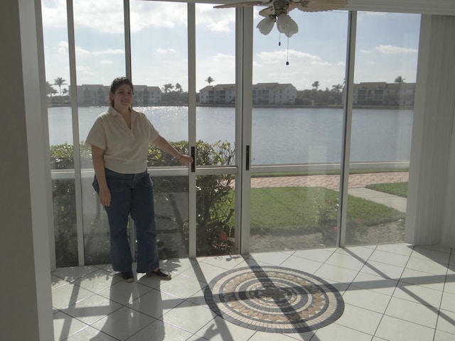 sunroom featuring ceiling fan, a healthy amount of sunlight, and a water view