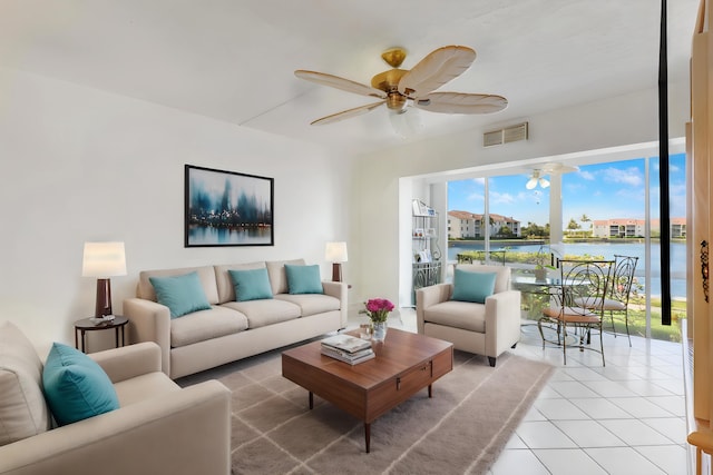 tiled living room with ceiling fan and a water view