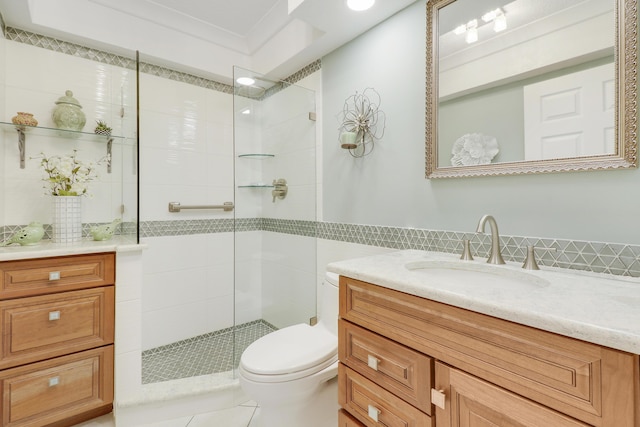 bathroom featuring tile patterned flooring, toilet, tiled shower, vanity, and tile walls