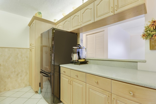 kitchen with black fridge, kitchen peninsula, light brown cabinetry, and light tile patterned floors