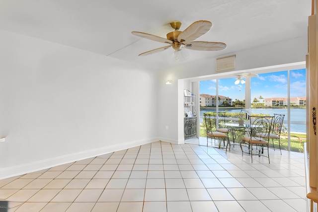 spare room featuring a water view, light tile patterned floors, and ceiling fan