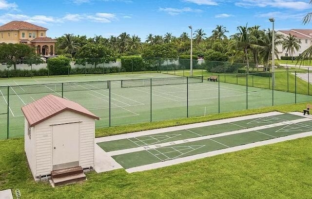 view of community featuring tennis court, a lawn, and a water view