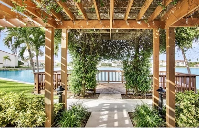 view of patio / terrace with a deck with water view and a pergola