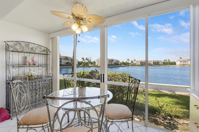 sunroom / solarium with ceiling fan and a water view