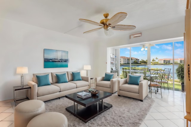 living room with ceiling fan, light tile patterned floors, and a water view