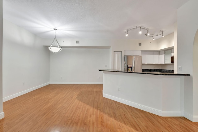 kitchen featuring pendant lighting, light wood-type flooring, white cabinetry, rail lighting, and stainless steel fridge