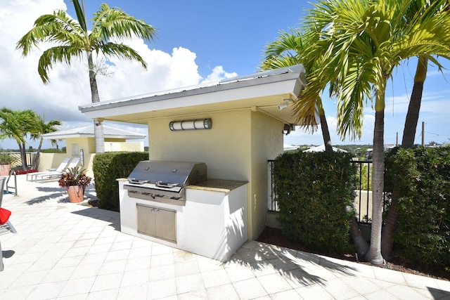 view of terrace with exterior kitchen and a grill