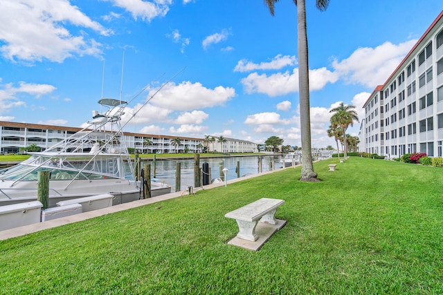 view of dock with a lawn and a water view